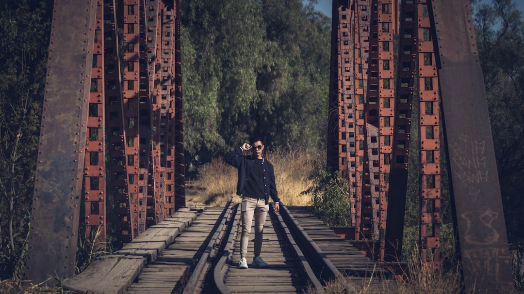man in black jacket walking on train rail during daytime