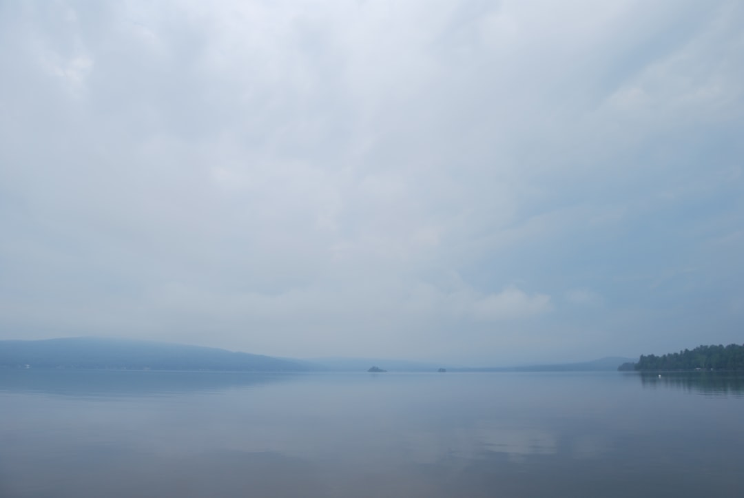 A body of water surrounded by trees and clouds