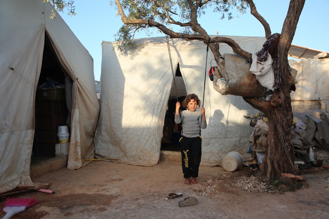 A woman standing next to a tree in front of a tent